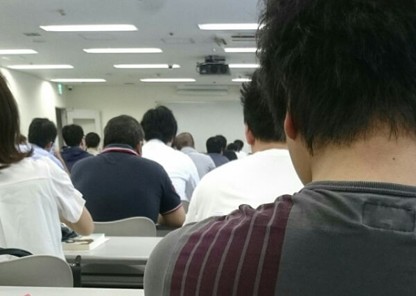 男性の肩越しに広がるセミナーの風景